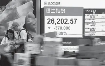  ??  ?? 10月8日，行人从香港中环街头的­股市信息屏前经过。当日，恒指下跌370点，跌幅1.39%，报收26202.57点 新华社图