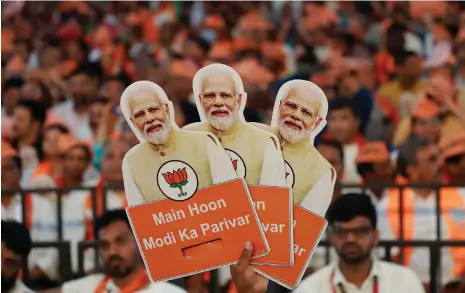  ?? Reuters ?? A Bharatiya Janata Party supporter holds cutouts of Prime Minister Narendra Modi during a campaign event in Bengaluru