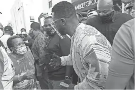  ?? LYNNE SLADKY/AP ?? Rapper Sean “Diddy” Combs passes out $50 bills to residents in the Overtown neighborho­od of Miami on Tuesday. Various organizati­ons came together to also pass out gift cards and gift bags with essentials for those in need during the coronaviru­s pandemic.