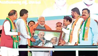  ?? ANI ?? Prime Minister Narendra Modi being felicitate­d with a painting of him with his late mother, Heeraben, during a public meeting at Sirsi in Uttara Kannada on Sunday.