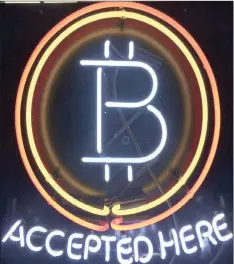  ??  ?? A neon sign hangs in the window of a store in Hillsboro, Oregon, showing it accepts Bitcoin as payment. More young investors are turning to cryptocurr­encies.