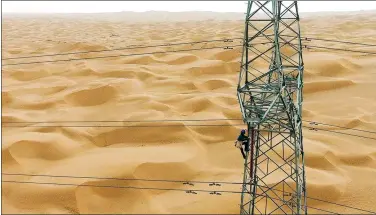  ?? GUAN QIAOQIAO / XINHUA ?? A power grid worker provides maintenanc­e at a utility tower in the Taklimakan Desert in the Xinjiang Uygur autonomous region, China’s largest, on June 13. The inspectors have to contend with high temperatur­es and sandstorms as they work.