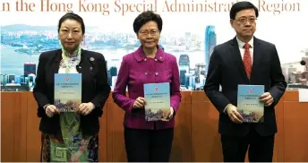  ??  ?? Lam (centre) poses with Justice Secretary Teresa Cheng (le ) and Lee (right) while holding copies of the new national security law during a press conference at the government headquarte­rs in Hong Kong.