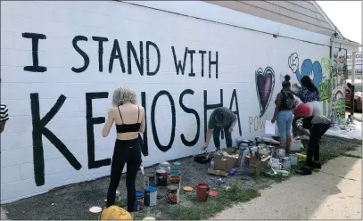  ?? The Associated Press ?? Volunteers paint murals on boarded-up businesses in Kenosha, Wis., on Sunday at an “Uptown Revival.”