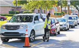  ?? WILFREDO LEE AP ?? Prudence Swift directs cars and hands out unemployme­nt informatio­n at a food distributi­on event this week in Opa-locka, Fla., hosted by Feeding South Florida.