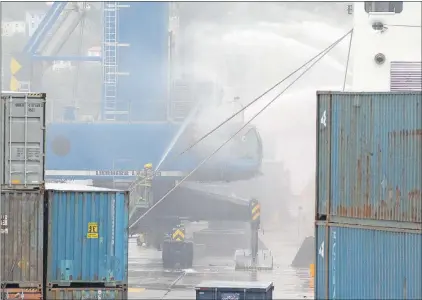  ?? KEITH GOSSE/THE TELEGRAM ?? Firefighte­rs with the St. John's Regional Fire Department hose down hotspots from a fire on an Oceanex crane Monday at St. John’s harbour.