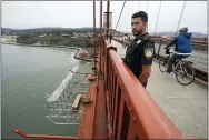  ?? ERIC RISBERG—ASSOCIATED PRESS ?? In this Aug. 3, 2021, photo Patrol officer Nicolas Serrano looks out at a suicide barrier under constructi­on below the Golden Gate Bridge in San Francisco. In recent years, officials who oversee so-called suicide hotspots like San Francisco’s Golden Gate Bridge and the George Washington Bridge, which spans New York City and New Jersey, have worked to install prevention or deterrent systems.