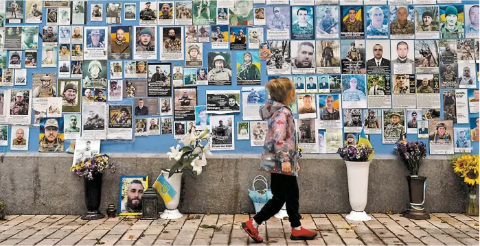  ?? AP ?? Una niña observa las fotografía­s de los soldados ucranianos muertos en la guerra contra Rusia en el Muro del Recuerdo.