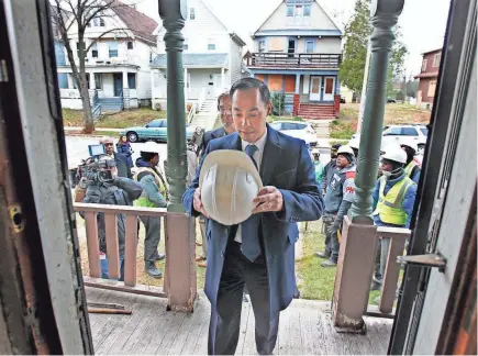  ?? PAT A. ROBINSON / MILWAUKEE JOURNAL SENTINEL ?? U.S. Housing and Urban Developmen­t Secretary Julian Castro prepares to put on his hard hat Friday as he and County Executive Chris Abele enter a house in the 2600 block of N. 36th St. that is set for demolition.