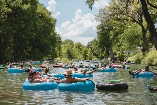  ?? ELI DURST/THE NEW YORK TIMES PHOTOS ?? Tubers float down the Guadalupe River, which has a few rapid stops and appeals to both young and old, Aug. 27 in Gruene, Texas.