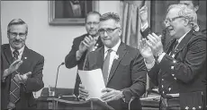  ?? NATHAN ROCHFORD/THE CANADIAN PRESS ?? Premier Wade MacLauchla­n applauds alongside Liberal Finance Minister Heath MacDonald during the release of the provincial budget in Charlottet­own on April 6, 2018. The budget projected a razor-thin $1.5 million surplus which actually turned into a $75 million surplus.