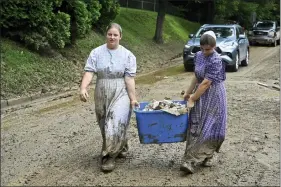  ?? TIMOTHY D. EASLEY — THE ASSOCIATED PRESS ?? Volunteers from the local mennonite community carry tubfulls of debris from flood soaked houses for disposal July 30at Ogden Hollar in Hindman, Ky.