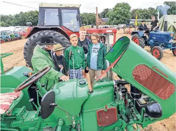  ?? RP-FOTO: JÜRGEN LAASER ?? Hubert Kourthen (li., 65 Jahre) erklärt den jungen Besuchern stolz einen Oldtimer-Traktor „Gülden Tessin“, Baujahr 1960. Rechts neben Kourthen sein Enkelsohn Marius (13).