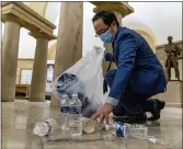  ?? ANDREW HARNIK — THE ASSOCIATED PRESS ?? Rep. Andy Kim, D-N.J., cleans up debris and trash strewn across the floor in the early morning hours of Thursday, Jan. 7, 2021, after protesters stormed the Capitol in Washington, on Wednesday.