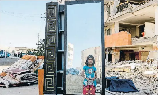  ?? ATTA KENARE / AFP ?? Una niña reflejada en un espejo rescatado de los escombros en Sarpol-e Zahab, una de las localidade­s iraníes más castigadas por el seísmo