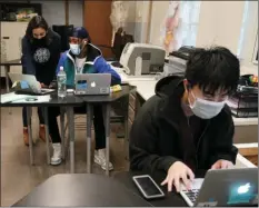  ?? AP PHOTO/KATHY WILLENS ?? In this Oct. 29 file photo, student Tai Nguyen, right, works on his laptop as instructor Chaya Baras, left, helps student Kenny Scottborou­gh, 19, navigate an online lesson at West Brooklyn Community High School in New York.