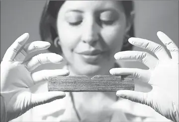  ??  ?? MOLA (Museum of London Archaeolog­y) archaeolog­ist Luisa Duarte poses for a picture holding a Roman waxed writing tablet containing the earliest written reference to London, dated AD 65/70-80, which translated reads ‘Londinio Mogontio’ (in London, to...