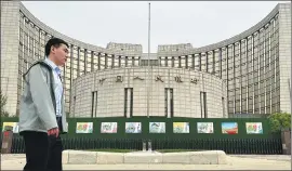  ?? ?? A pedestrian walks past the headquarte­rs of the PBOC in Beijing.