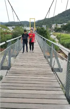  ??  ?? The ‘younger’ group members Maxson and Anthony (left) walk across the famous bridge in Tamparuli.