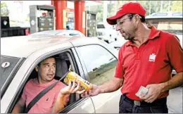  ?? ARIANA CUBILLOS/AP ?? Orlando Godoy takes a package of corn flour as payment at a gas station near Caracas.