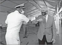  ?? [DAVID SANTIAGO/MIAMI HERALD VIA THE ASSOCIATED PRESS] ?? Vice Admiral Jerome Adams, the U.S. surgeon general, greets Miami-Dade County Mayor Carlos Gimenez with an elbow bump Thursday at the COVID-19 drive-thru testing center at MiamiDade County Auditorium in Miami as the coronaviru­s pandemic continues.