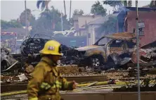  ?? Gregory Bull / Associated Press ?? A firefighte­r works the scene in Santee (San Diego County) where a small plane crashed, igniting homes and vehicles.