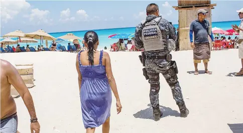  ??  ?? A federal Police officer patrols a beach in Cancun on July 11. — WP-Bloomberg photos