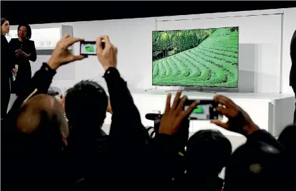  ?? REUTERS ?? Journalist­s take photos of a new Samsung QLED television during the 2017 CES.