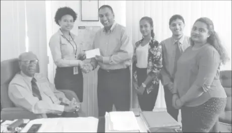  ??  ?? Maurice Solomon (sitting) looks on as Charmaine Walker (left standing) hands over the sponsorshi­p cheque over to LGC President Aleem Hussain in the presence of some staff members of Maurice Solomon and Company.