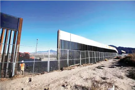  ??  ?? A worker stands next to a section of the border fence in Sunland Park, New Mexico. (Reuters file photo)