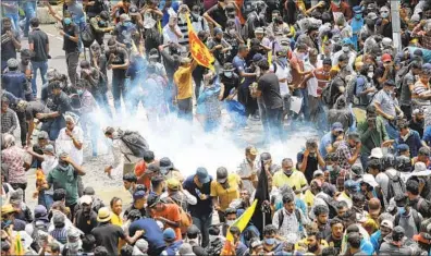  ?? Amitha Thennakoon Associated Press ?? PROTESTERS REACT as a tear gas canister lands next to them in Colombo, Sri Lanka, on Saturday.