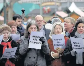  ??  ?? > A mixed choir of locals and refugees sing in support of Berlin near the site where the Christmas market attack happened