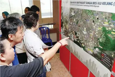  ??  ?? Checking out: Members of the public who attended the public briefing taking a closer look at maps showing the alignment of the highway.