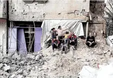  ?? ?? Palestinia­ns sit amid debris following overnight Israeli bombardmen­t in Rafah.