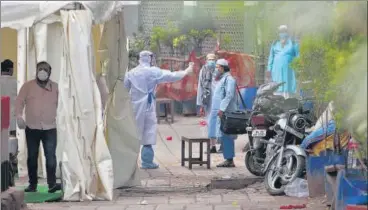  ?? ANI ?? A volunteer wearing a protective suit checks the temperatur­e of a man in Nizamuddin area of New Delhi on Monday. >>P2 n