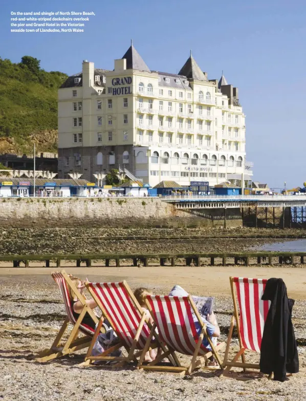  ??  ?? On the sand and shingle of North Shore Beach, red-and-white-striped deckchairs overlook the pier and Grand Hotel in the Victorian seaside town of Llandudno, North Wales