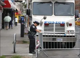 ?? SETH WENIG — ASSOCIATED PRESS ?? A police officer works near the site where an officer was killed in the Bronx on Thursday. Police officer Miosotis Familia was shot to death early Wednesday, ambushed inside her command post by an ex-convict, authoritie­s said. He was later killed after...