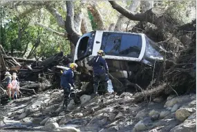  ?? AP PHOTO BY MARCIO JOSE SANCHEZ ?? Members of the Los Angeles County Fire Department Search and Rescue crew work on a car trapped under debris in Montecito Wednesday.