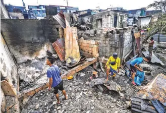  ??  ?? PICKING UP THE PIECES – Residents of Eastbank Road, Floodway in Cainta, Rizal, rummage through the rubble of what used to be their homes on Saturday after a fire razed the area Friday night. (Alvin Kasiban)