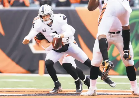  ?? Andy Lyons / Getty Images ?? Quarterbac­k Derek Carr loses the ball as he’s sacked by Cincinnati defensive end Sam Hubbard in the first quarter Sunday.