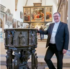  ??  ?? A la Stadtkirch­e Sankt Marien de Wittenberg, le pasteur Christian Beuchel pose devant les fonts baptismaux du XVe siècle et le retable de Cranach l’Ancien (au fond).