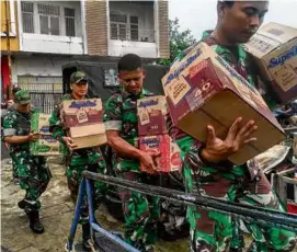  ?? RONNY ADOLOF BUOL/AFP VIA GETTY IMAGES ?? Indonesian military personnel loaded items onto a ship on Thursday as they raced to evacuate thousands of people near Mount Ruang volcano in North Sulawesi.