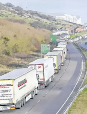  ??  ?? DOVER, England — The Dover Traffic Access Protocol (TAP) scheme on the A20 is seen in action as freight lorries queue on the main route into the port of Dover on the south coast of England on December 18, 2020 with the White Cliffs and a ferry in the background.