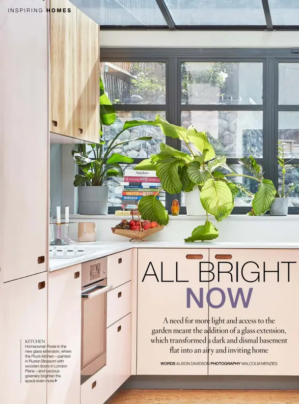  ??  ?? KITCHEN
Homeowner Rosie in the new glass extension, where the Pluck kitchen – painted in Ruskin Blossom with wooden doors in London Plane – and luscious greenery brighten the space even more