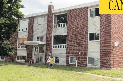  ?? STEPHEN MACGILLIVR­AY / THE CANADIAN PRESS ?? A family gathers outside of a Fredericto­n apartment building complex where four people were killed, including two police officers, in a shooting last Friday. Police removed barricades and allowed residents to return on Tuesday.