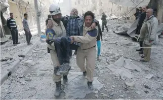  ?? ZEIN AL-RIFAI/AFP/GETTY IMAGES ?? Emergency personnel carry an injured man Friday following air strikes by government helicopter­s on the eastern Shaar neighbourh­ood of Aleppo in northern Syria.