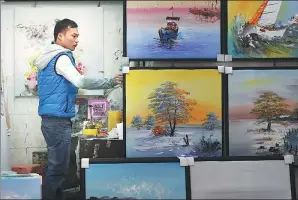 ?? XU YUANCHANG / FOR CHINA DAILY ?? A worker arranges oil paintings at an art gallery in Dafen. Liu Yajing, director of Dafen’s management office