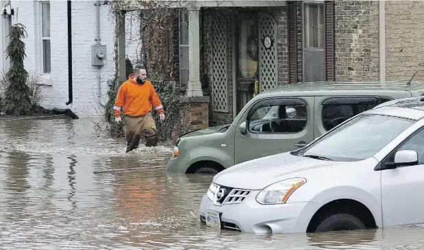  ?? BRIAN THOMPSON / POSTMEDIA NEWS ?? Water rushes down Grand River Street in Brantford, Ont., Wednesday after an ice jam on the Grand River gave way following warm temperatur­es and heavy rains. The city declared a state of emergency and about 4,900 people in roughly 2,200 homes are under...