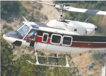  ??  ?? A pilot manoeuvres a helicopter water bomber near a wildfire
in the area of Lytton, B.C., on Saturday.