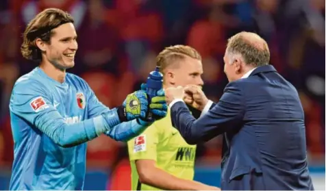  ?? Foto: Federico Gambarini, dpa ?? Augsburger Freude: Torhüter Marwin Hitz und Manager Stefan Reuter nach dem Schlusspfi­ff in Leverkusen.